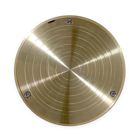 A drain cleanout inspection point with a stainless steel or brass-colored circular lid and a push-fit 100mm PVC pipe, set against a black striped background.