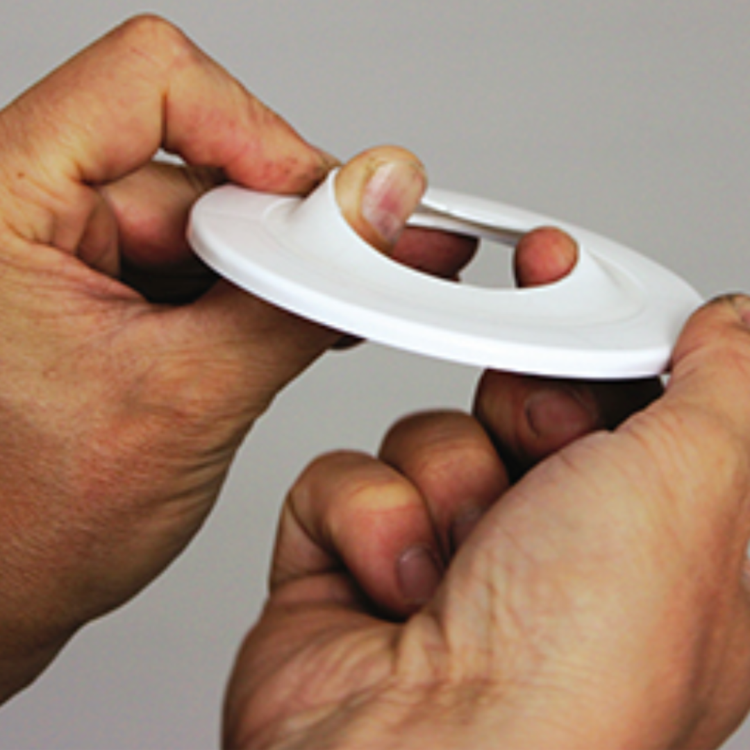 A person's hands holding a white Flexy Flange round seal for pipes.