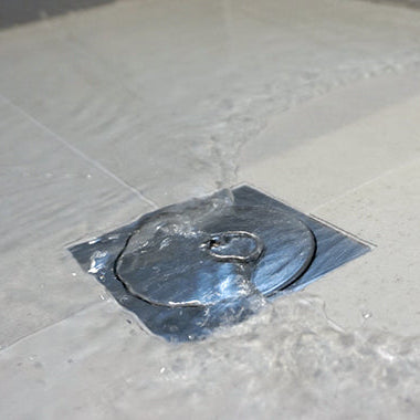 A chrome tile floor waste plug installed on a wet surface, presumably part of a leak control system.